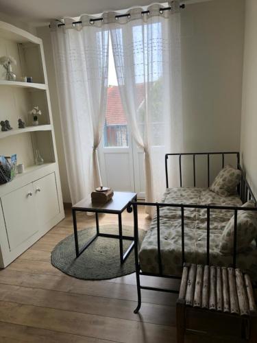 1 dormitorio con cama, mesa y ventana en Burin des rosiers, en Olby