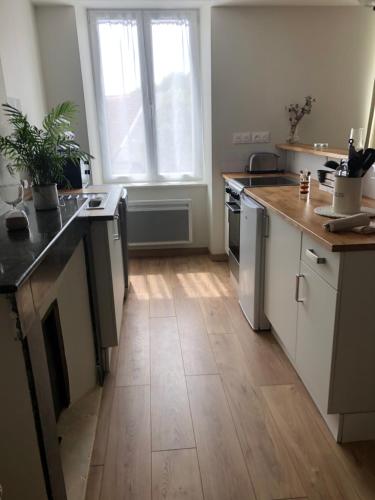 a kitchen with white cabinets and a wooden floor at Burin des rosiers in Olby