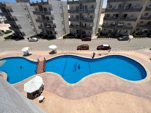 a large swimming pool in a parking lot with buildings at Tahiti Bay in Marsa Matruh