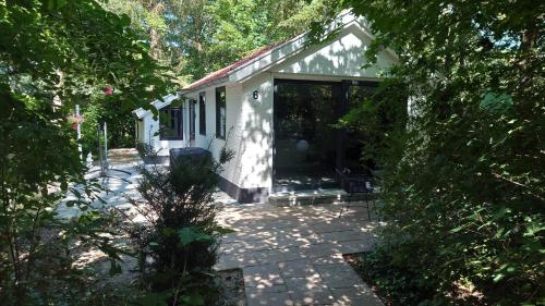 a white house with a large sliding glass door at Relaxed Luxe "Boszichthuisje" met Jacuzzi Bospark Ijsselheide Hattemerbroek in Hattemerbroek