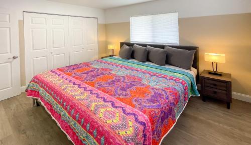 um quarto com uma cama grande e um cobertor colorido em Lazy Cuckoo Inn - Sleek and Stylish Studio Apartments em Fort Myers Beach