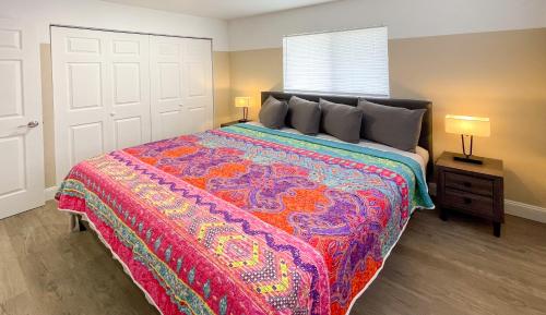 a bedroom with a large bed with a colorful blanket at Lazy Cuckoo Inn - Sleek and Stylish Studio Apartments in Fort Myers Beach