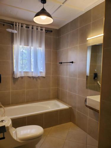 a bathroom with a tub and a toilet and a sink at Mangos Villas - Lucia in Kilifi