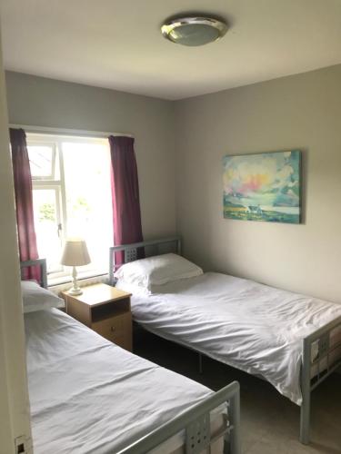 1 dormitorio con 2 camas y ventana en Ballymacdoe Cottage Cushendall, en Cushendall