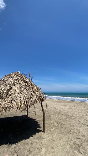 a straw umbrella on a beach near the ocean at Villa Mediterránea in Tubará