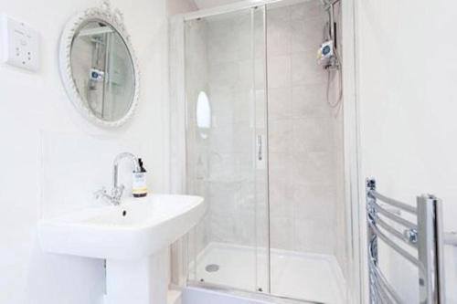 a white bathroom with a sink and a shower at The Blackwater Suite in Colchester