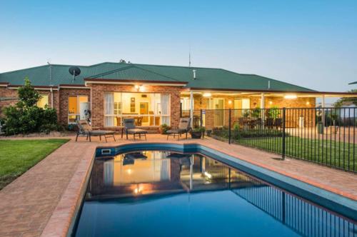 a house with a swimming pool in front of a house at Spacious resort style property with pool in Mudgee - Rest Easy Mudgee Villa in Mudgee