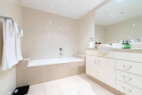 a white bathroom with a tub and a sink at Southport Sea Views - Shores Apartment in Gold Coast