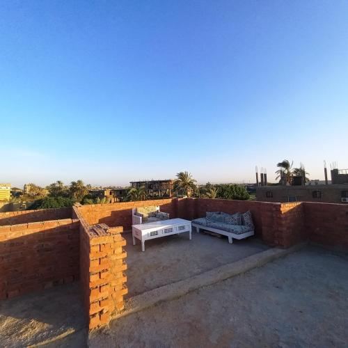 a patio with a table and a couch on a brick wall at Mystical habou domes villa private pool in Luxor