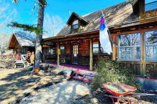 a log cabin with a bench and a flag at 3 Bedroom log cabin with hot tub at Bear Mountain in Eureka Springs