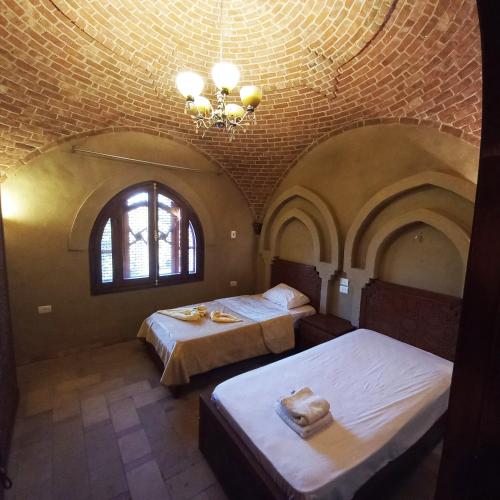 a bedroom with two beds and a chandelier at Mystical habou domes villa in Luxor