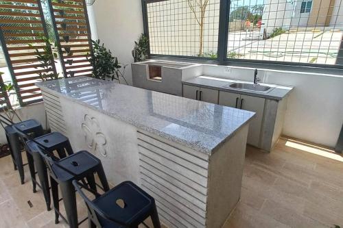 a kitchen with a counter with stools and a sink at 7F apartamento 3hab piscina ascensor y area social in Santiago de los Caballeros