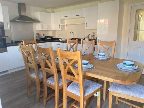 a wooden dining room table with chairs and a kitchen at Agase Way - Stylish 4 Bed Home in Milton Keynes