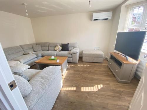 a living room with a couch and a flat screen tv at Agase Way - Stylish 4 Bed Home in Milton Keynes