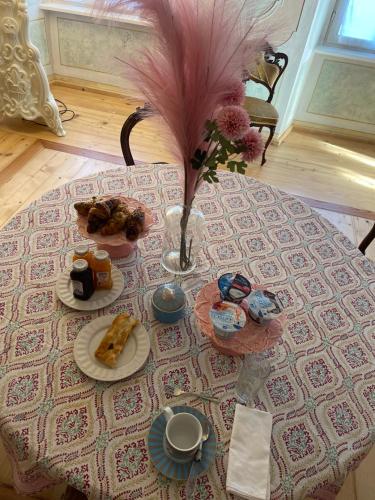 a table with a vase of feathers and food on it at La Cles Deluxe Suites in Cles