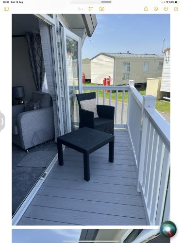 a black chair sitting on a deck with a couch at Carvan E102 in Steeple