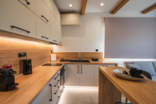 una cucina con armadi bianchi e ripiano in legno di Palaia Luxury Suite a Volos