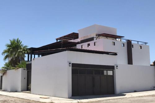 a white house with a gate and a palm tree at PB 2 recamaras, alberca y futbolito in San Carlos