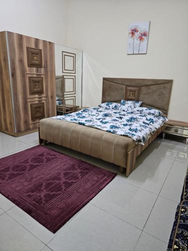 a bedroom with a bed and a purple rug at استوديو مفروس in As Sād