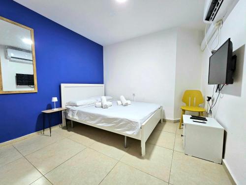1 dormitorio con cama blanca y pared azul en סוויטת מרלו - Merlot Suite, en Eilat