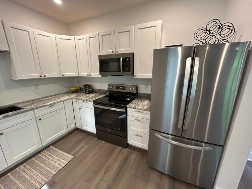 a kitchen with white cabinets and a stainless steel refrigerator at NEW 3 bedroom - Thoroughbred Farm & Lake Views! in Saratoga Springs