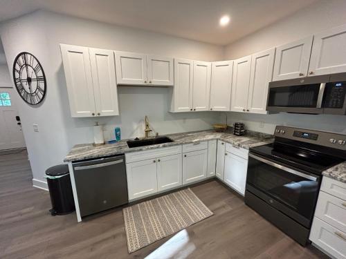 a kitchen with white cabinets and black appliances at NEW 3 bedroom - Thoroughbred Farm & Lake Views! in Saratoga Springs