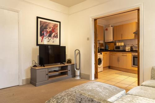 a living room with a television and a kitchen at Abeville Village Apartment in London