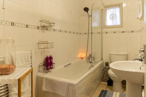 a bathroom with a tub and a toilet and a sink at Abeville Village Apartment in London