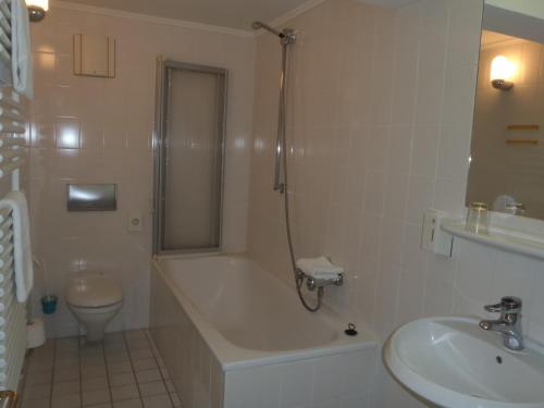 a bathroom with a tub and a toilet and a sink at Hotel am Buschkrugpark in Berlin