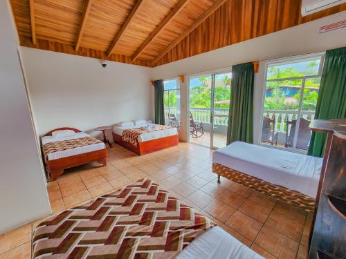 a bedroom with two beds and a balcony at Hotel Sierra Arenal in Fortuna