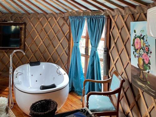 a bathroom with a tub and a chair and a window at Glamping montain experience in São Joaquim