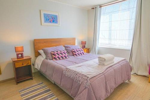 - une chambre avec un lit doté de draps violets et une fenêtre dans l'établissement TuArriendoCL-Vita A021 Centrico Depto Puerto Varas 1D1B hasta 3 PAX, à Puerto Varas