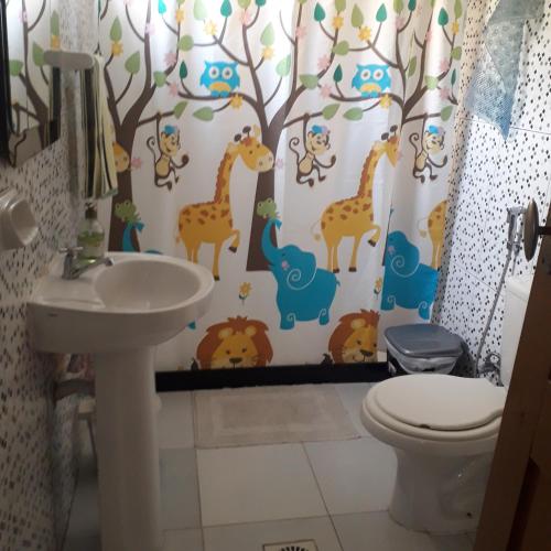 a bathroom with a shower curtain with giraffes and other animals at Madreselva in Xuí