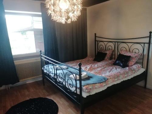 a bedroom with a black bed with a chandelier at Villa med egen parkering. Möjlighet att boka från 1 och upp till 5 personer. in Örebro