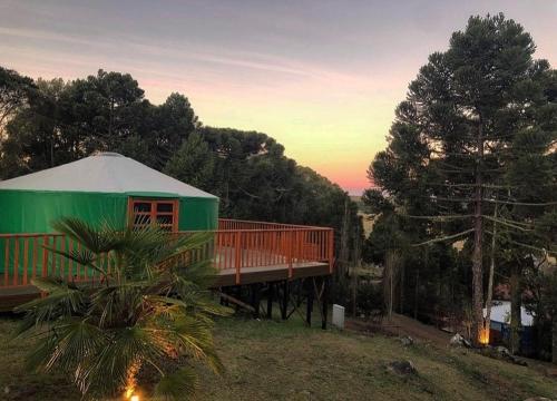 a green house with a deck and a tree at Solar do Oriente - Yurt Ecovillage in São Joaquim