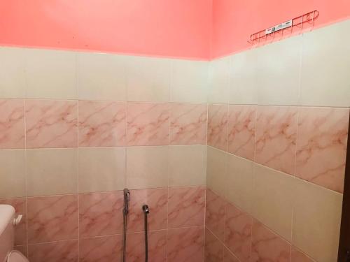 ein Bad mit rosa Marmorwänden und einer Dusche in der Unterkunft Chalet Sri Bayu in Kampong Balai Maras