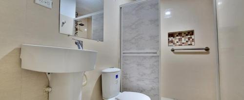 y baño blanco con aseo y ducha. en Extraordinaria CASA FINCA Piscina AA en Sabanalarga