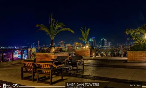 a group of chairs and tables on a rooftop at night at Condo in Manila