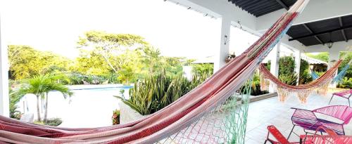 a porch with a hammock and chairs and a pool at Extraordinaria Casa Finca Piscina AA in Sabanalarga