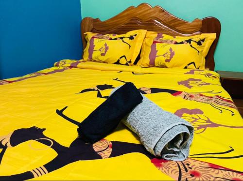 - un lit jaune avec une serviette dans l'établissement Complexe BEL AIR, à Bafoussam