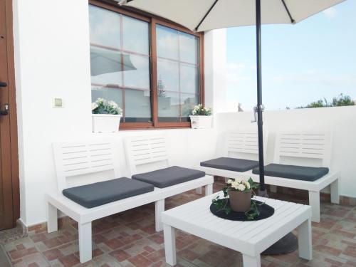 trzy ławki siedzące na ganku z parasolką w obiekcie Casa Isabel w mieście Playa Honda
