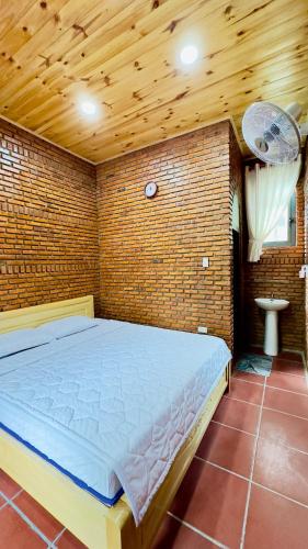 a bedroom with a large bed in a brick wall at Da Let Homestay & Coffee in Hiệp Mỹ