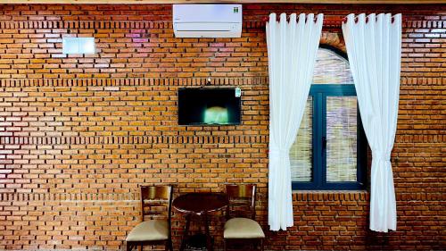 a brick wall with white curtains and chairs and a window at Da Let House & Coffee 