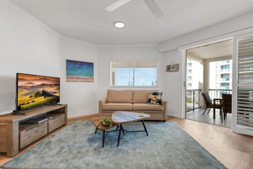 a living room with a couch and a tv at Raffles Mooloolaba in Mooloolaba