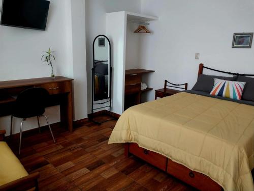 a bedroom with a bed and a desk and a mirror at Spondylus in Huanchaco