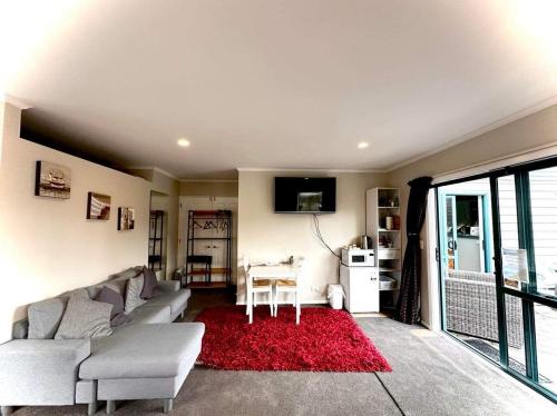 a living room with a couch and a red rug at Observation Guest Suite in Paraparaumu