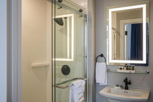 a bathroom with a shower and a sink and a mirror at BLU-Tique, Akron, a Tribute Portfolio Hotel in Akron