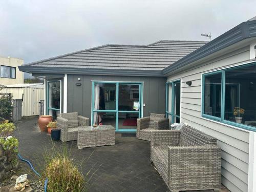 a patio with wicker chairs in front of a house at Observation Guest Suite in Paraparaumu