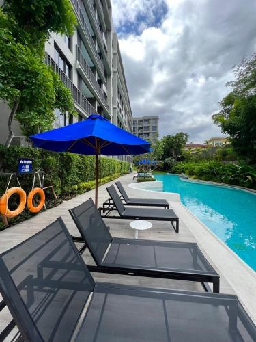 eine Terrasse mit Stühlen, einem Sonnenschirm und einem Pool in der Unterkunft Marvest Condo Hua Hin for rent in Hua Hin