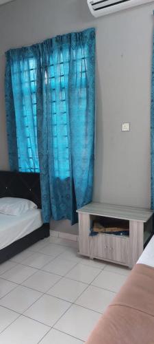 a room with a bed and a window with blue curtains at Sobey Laris Roomstay IMAN GMC in Gua Musang